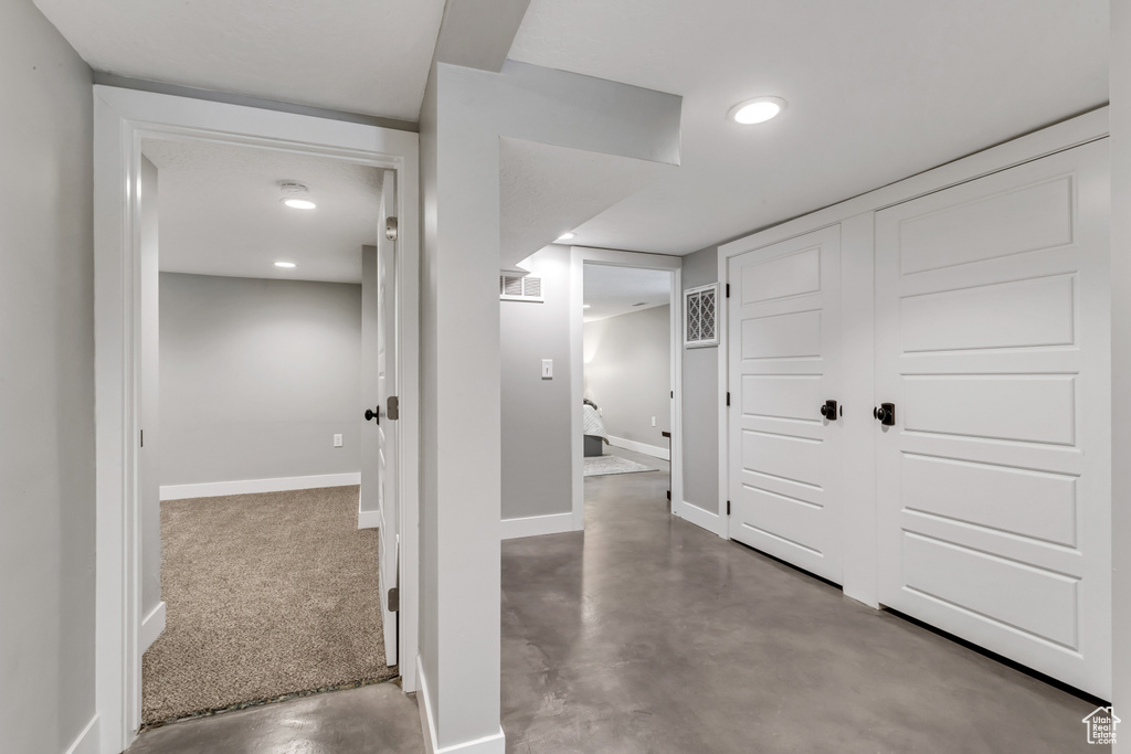 Hallway featuring baseboards, visible vents, concrete floors, and recessed lighting