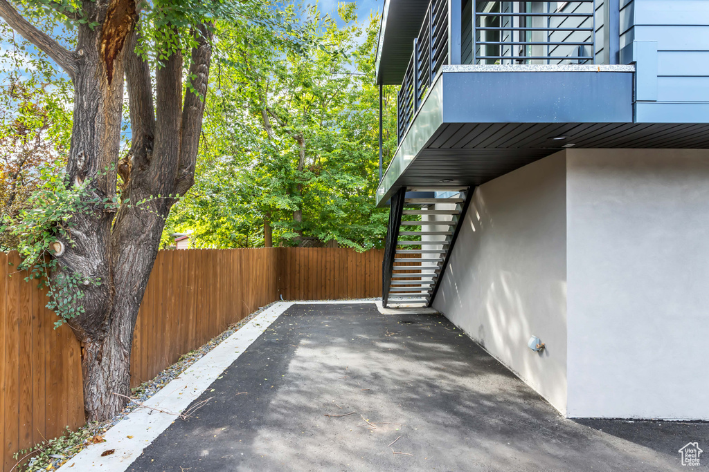 View of property exterior featuring stairway, a balcony, fence, and stucco siding