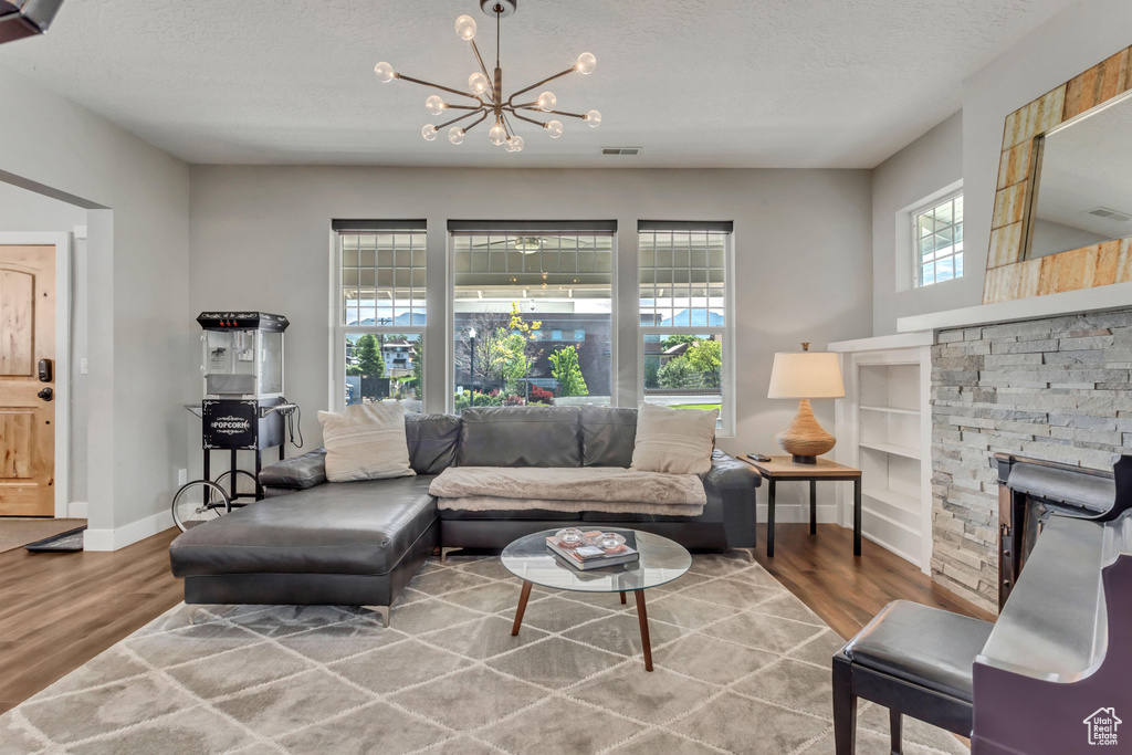 Living area with baseboards, a notable chandelier, wood finished floors, and a textured ceiling