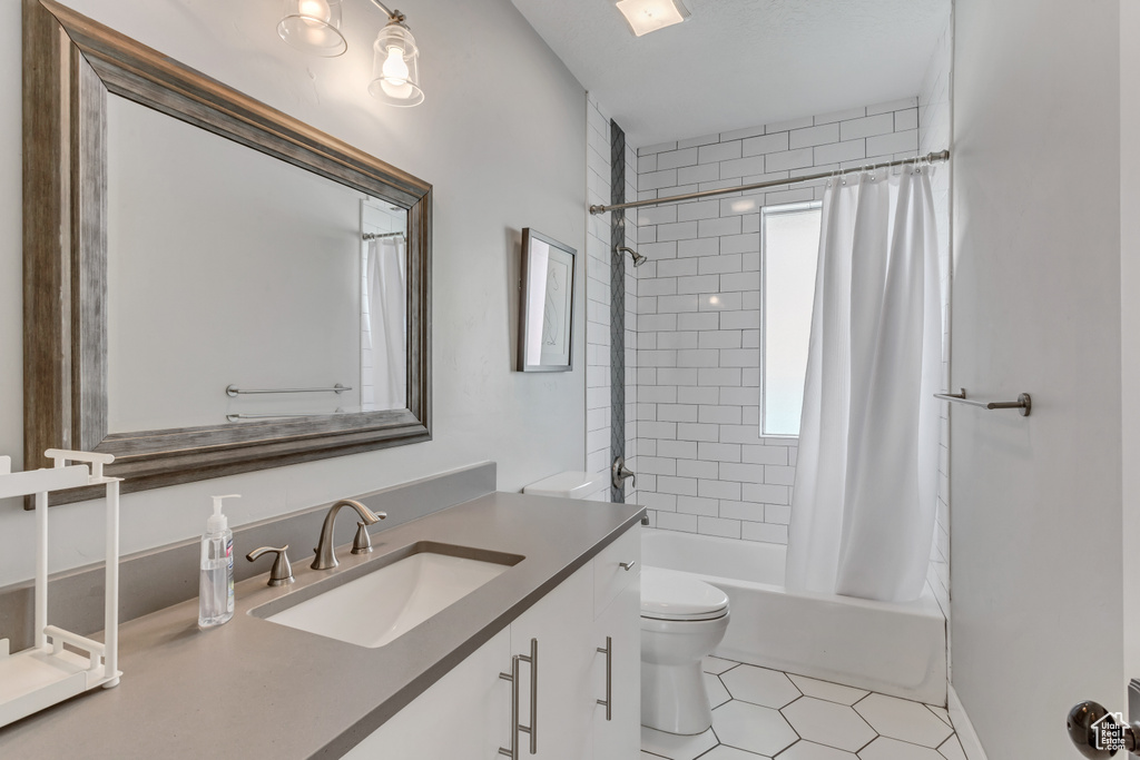 Full bath with toilet, vanity, tile patterned floors, and shower / bathtub combination with curtain