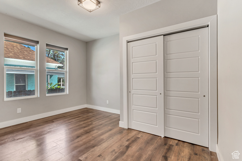 Unfurnished bedroom with baseboards, a closet, and dark wood finished floors