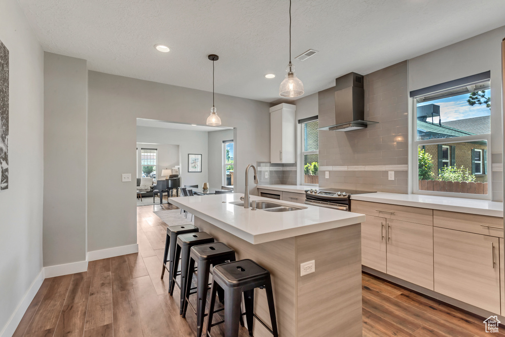 Kitchen with wall chimney range hood, a sink, stainless steel electric range oven, modern cabinets, and recessed lighting