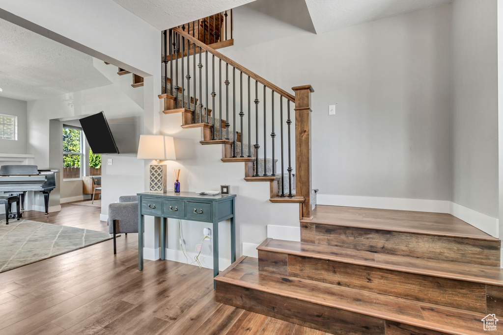 Staircase featuring baseboards, wood finished floors, and a textured ceiling