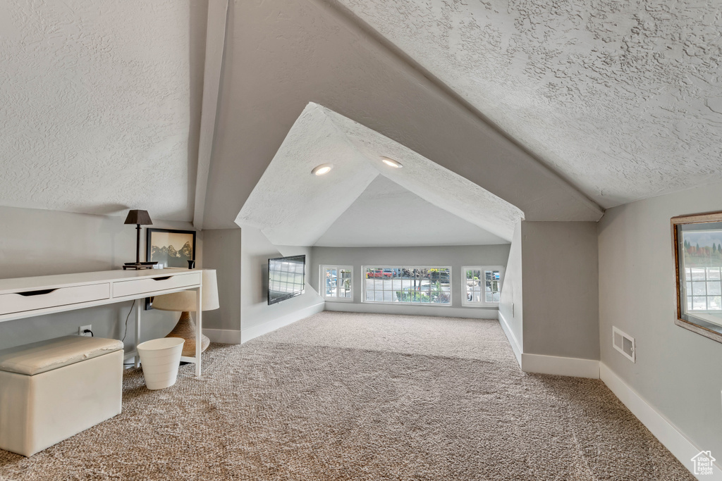 Bonus room featuring vaulted ceiling, a textured ceiling, carpet floors, and visible vents
