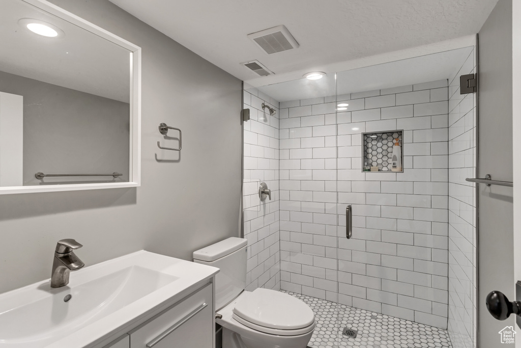 Full bath featuring toilet, vanity, visible vents, and a stall shower