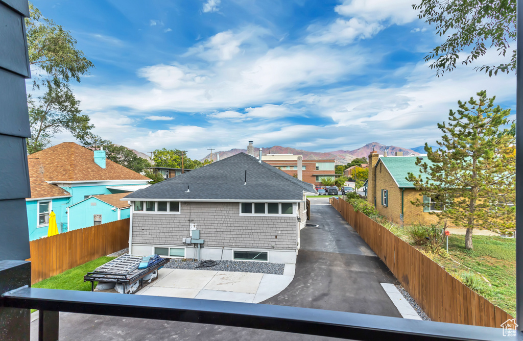 Back of property with a mountain view, fence, a shingled roof, and a residential view