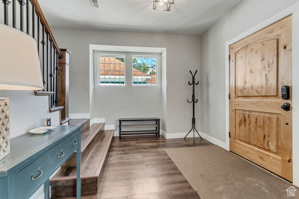 Foyer entrance featuring dark wood-style floors, stairway, a textured ceiling, and baseboards