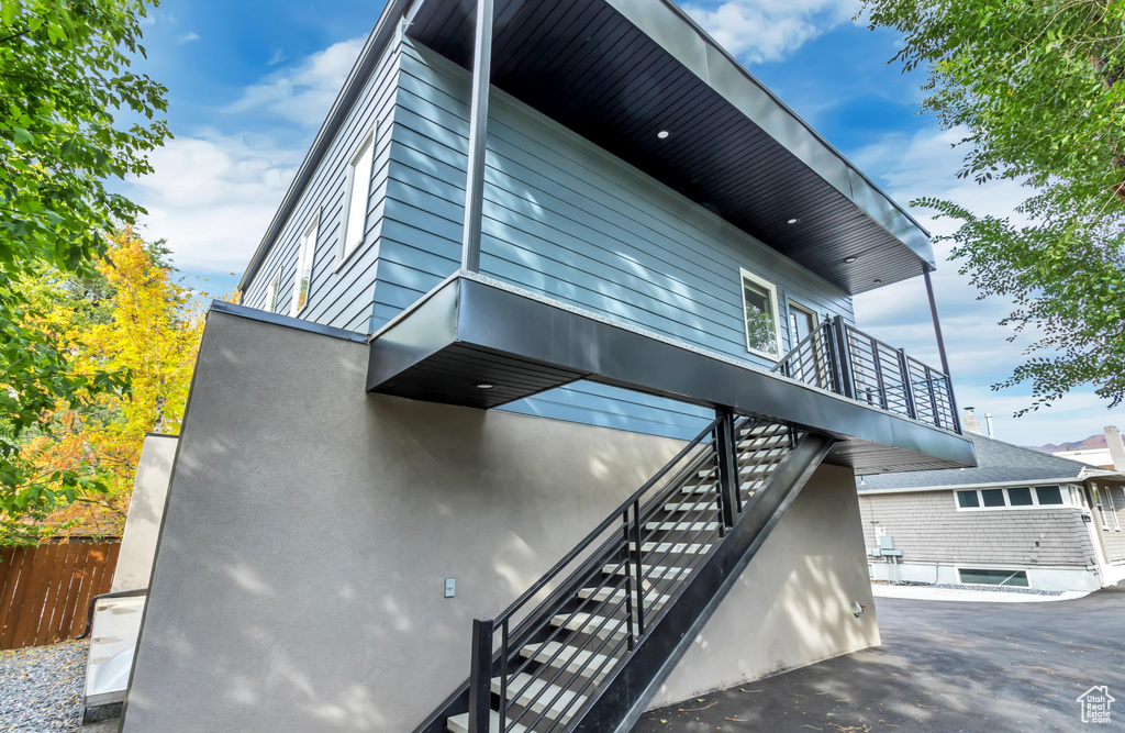 View of home\'s exterior featuring fence, stairway, and a balcony