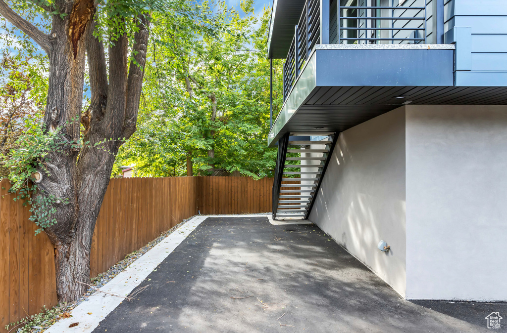 View of side of home with stairs, fence, a balcony, and stucco siding