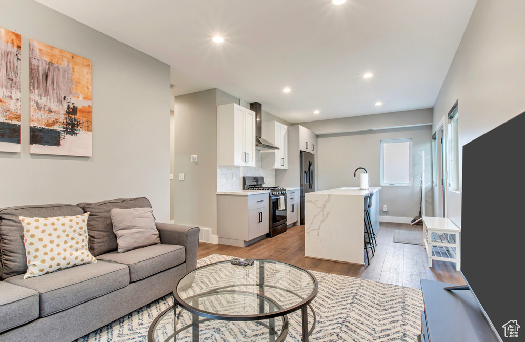 Living room with light wood finished floors, recessed lighting, and baseboards