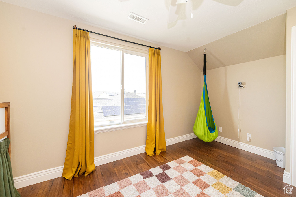 Unfurnished bedroom featuring wood finished floors, baseboards, vaulted ceiling, and ceiling fan