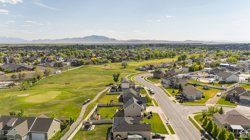 Aerial view of residential area featuring a mountainous background and a golf club