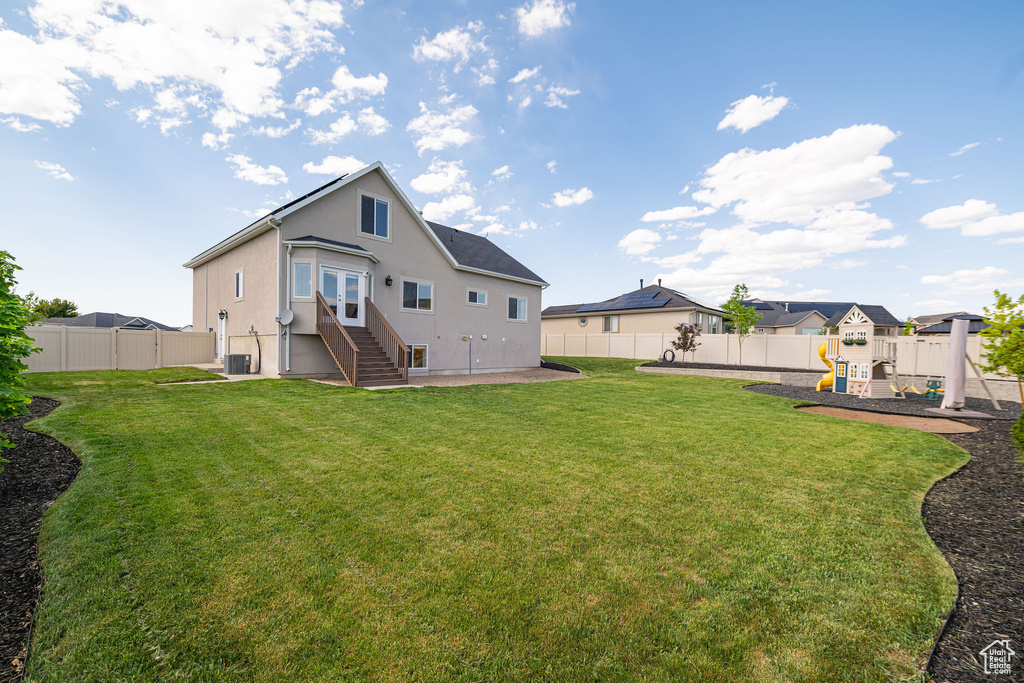 Rear view of house featuring entry steps, stucco siding, a patio, a playground, and french doors