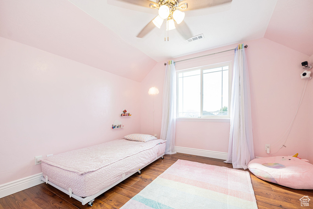 Bedroom with lofted ceiling, wood finished floors, baseboards, and a ceiling fan