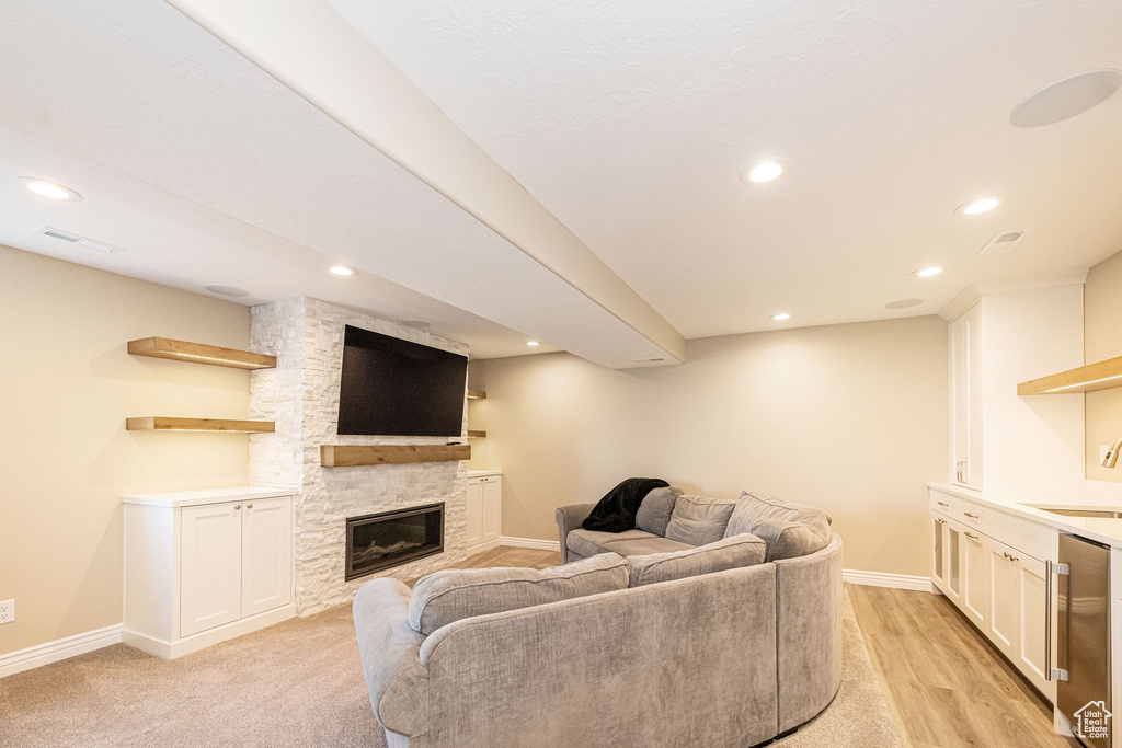 Living room featuring baseboards, recessed lighting, a fireplace, and light wood finished floors