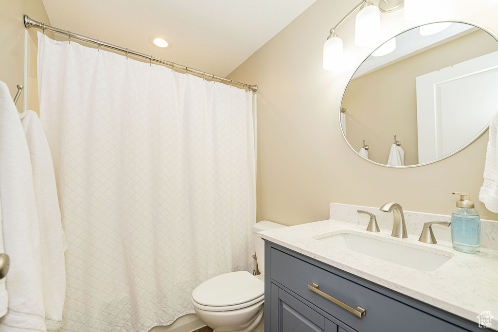 Bathroom with toilet, vanity, and curtained shower
