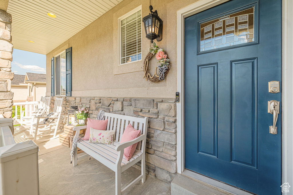 Property entrance featuring covered porch, stone siding, and stucco siding