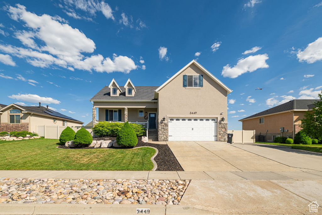 View of front facade featuring an attached garage, stone siding, concrete driveway, a porch, and stucco siding