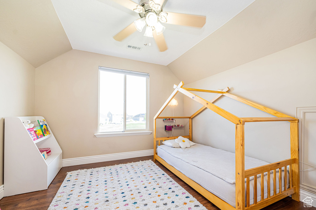 Bedroom featuring wood finished floors, lofted ceiling, a ceiling fan, and baseboards
