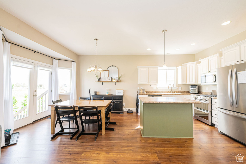 Kitchen with stainless steel appliances, a sink, a center island, white cabinetry, and recessed lighting