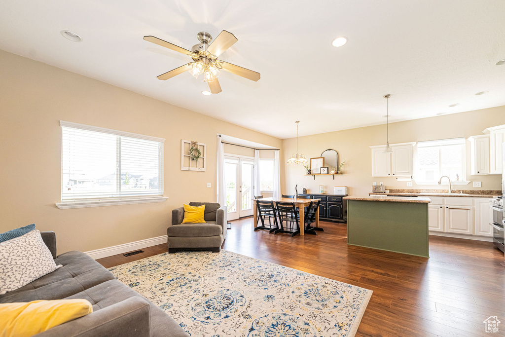 Living area with dark wood finished floors, ceiling fan, recessed lighting, baseboards, and a chandelier
