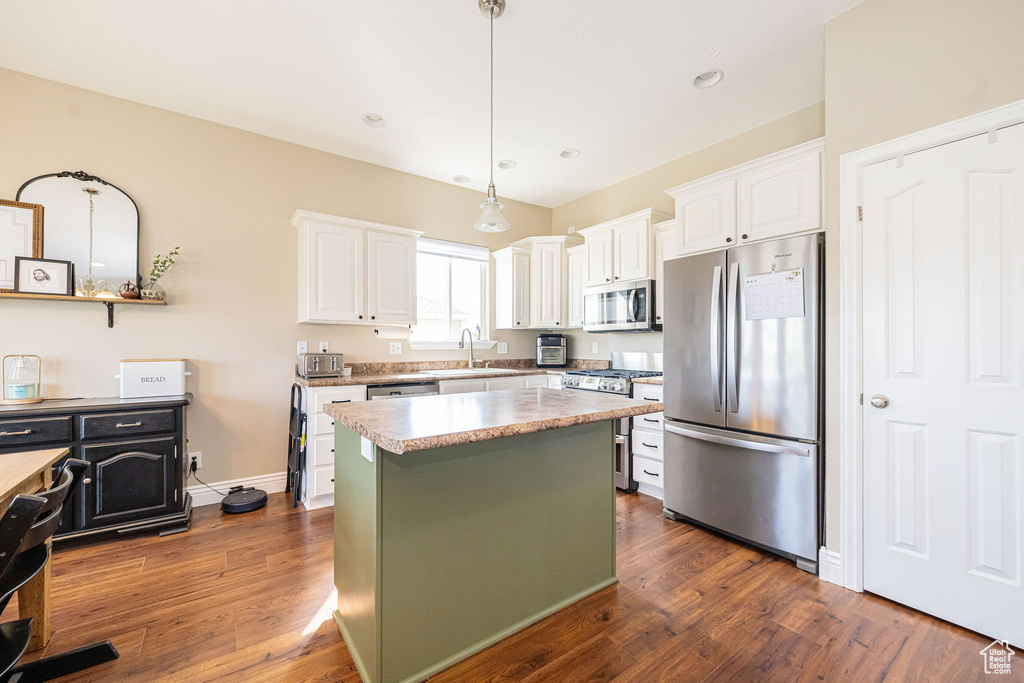 Kitchen with appliances with stainless steel finishes, a sink, white cabinetry, dark wood finished floors, and recessed lighting