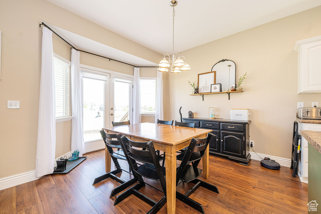 Dining room featuring dark wood-style floors, baseboards, a chandelier, and french doors