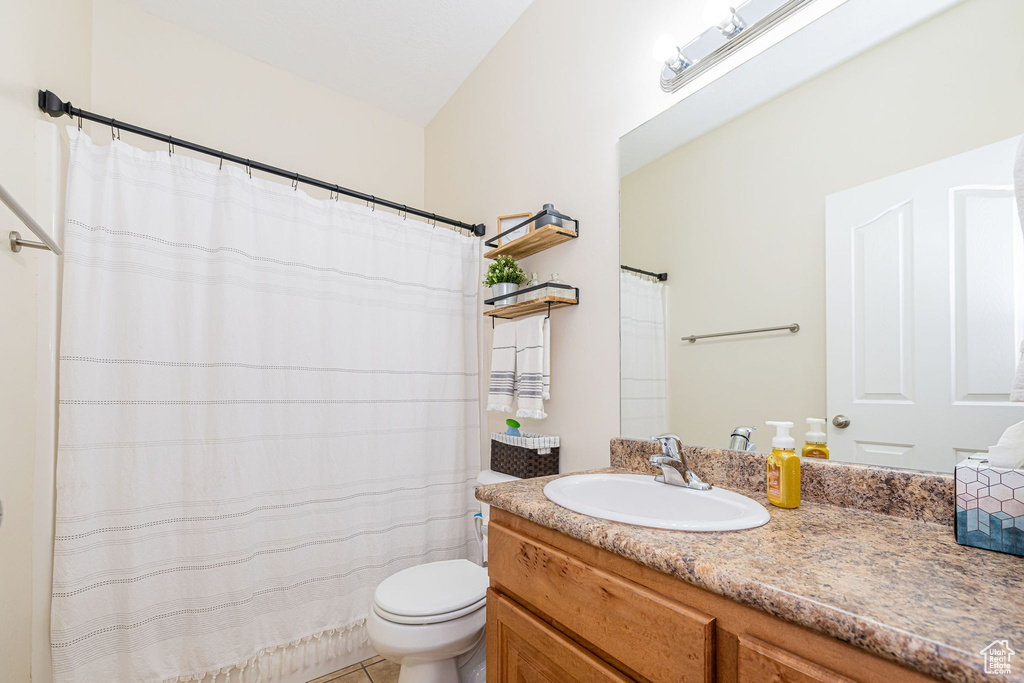 Bathroom featuring vanity, toilet, and curtained shower