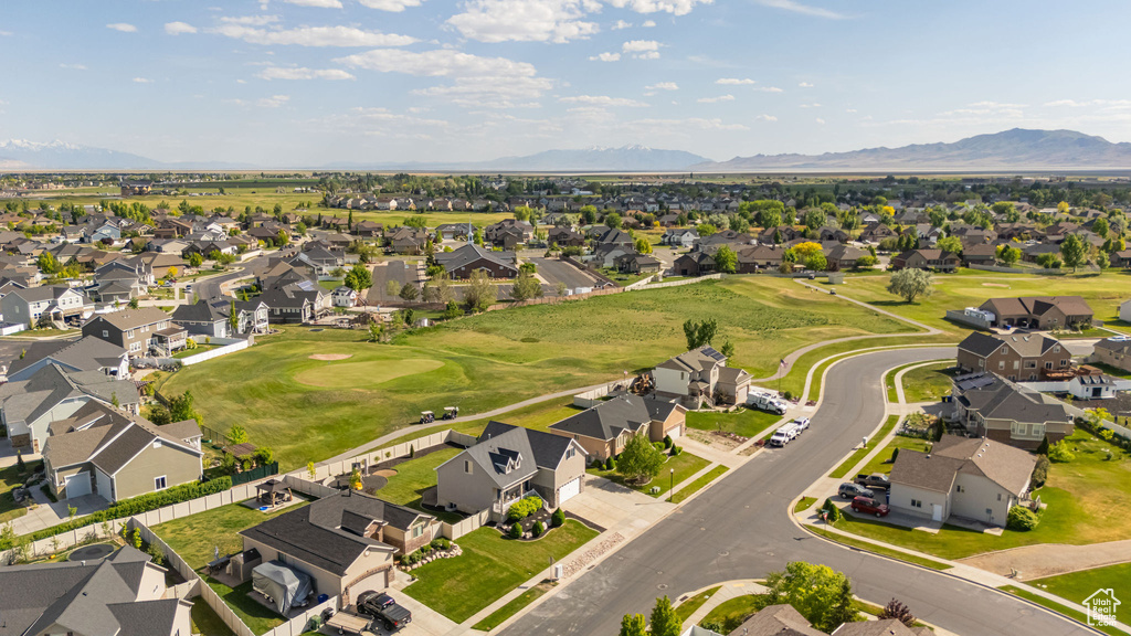 Aerial view of property and surrounding area featuring nearby suburban area, mountains, and a golf course