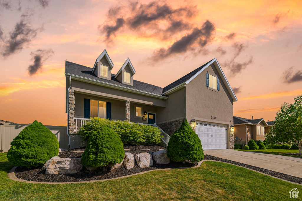 View of front facade featuring stone siding, a garage, a porch, concrete driveway, and stucco siding