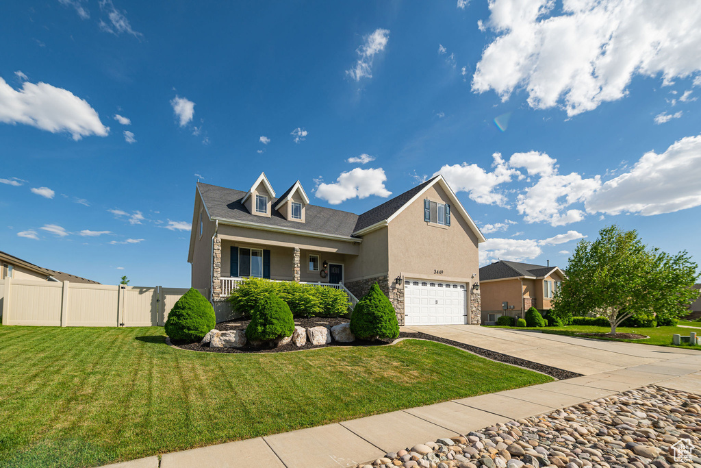 Traditional-style home featuring a garage, driveway, stone siding, stucco siding, and covered porch