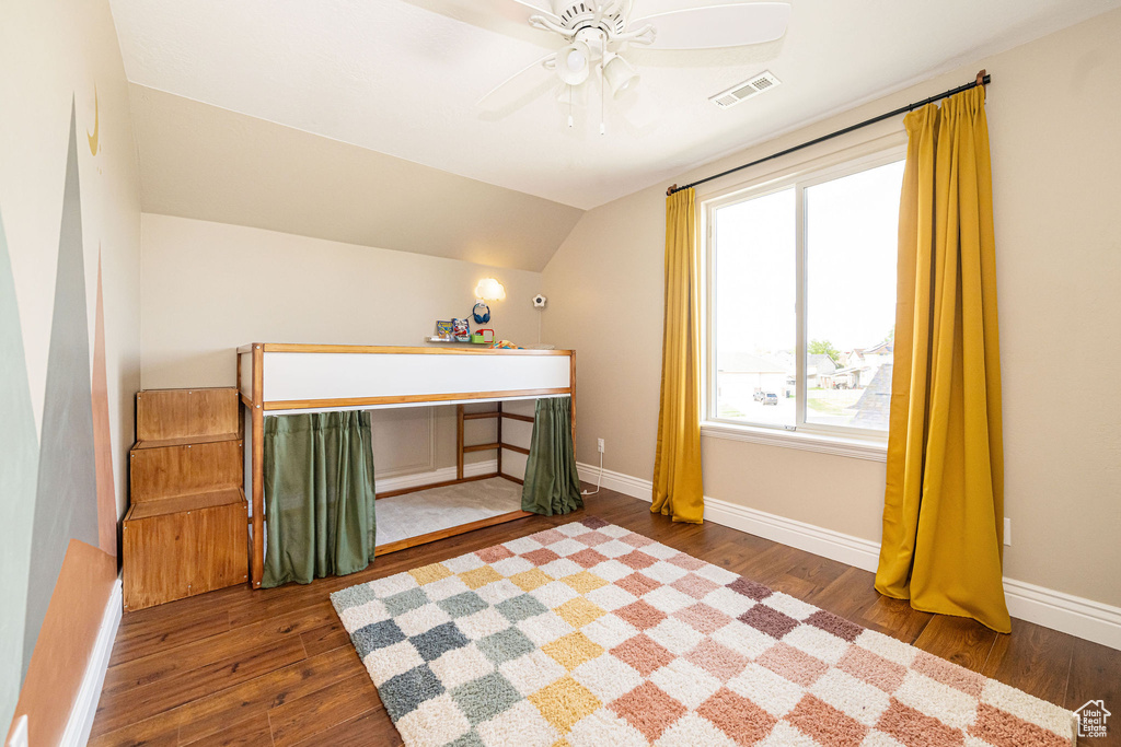 Bedroom featuring wood finished floors, vaulted ceiling, baseboards, and ceiling fan