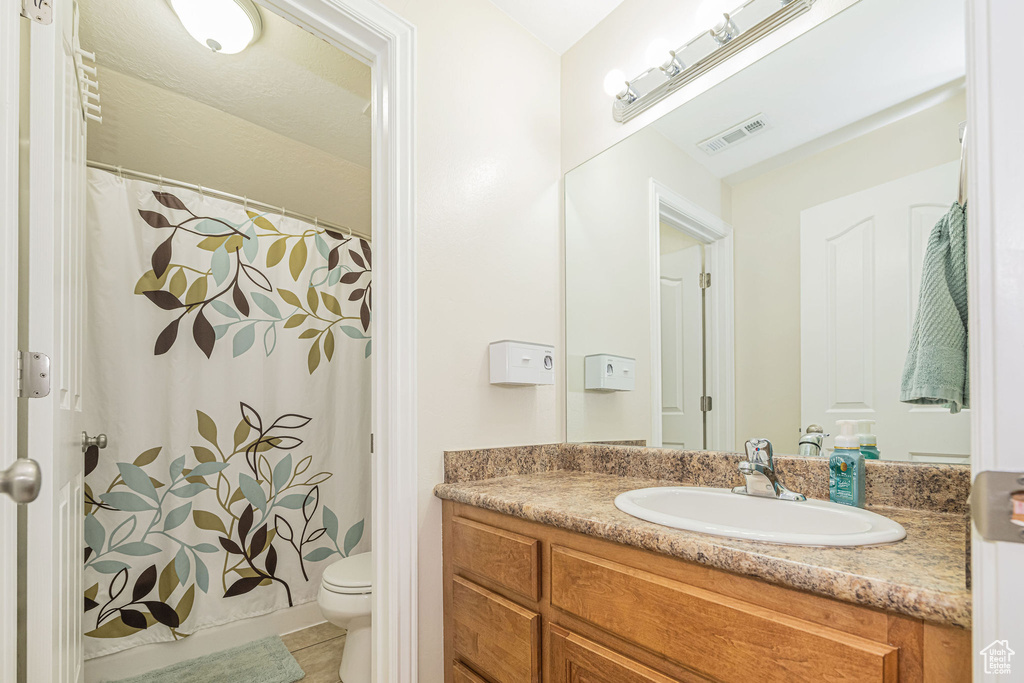 Bathroom featuring toilet, vanity, a shower with curtain, and tile patterned flooring