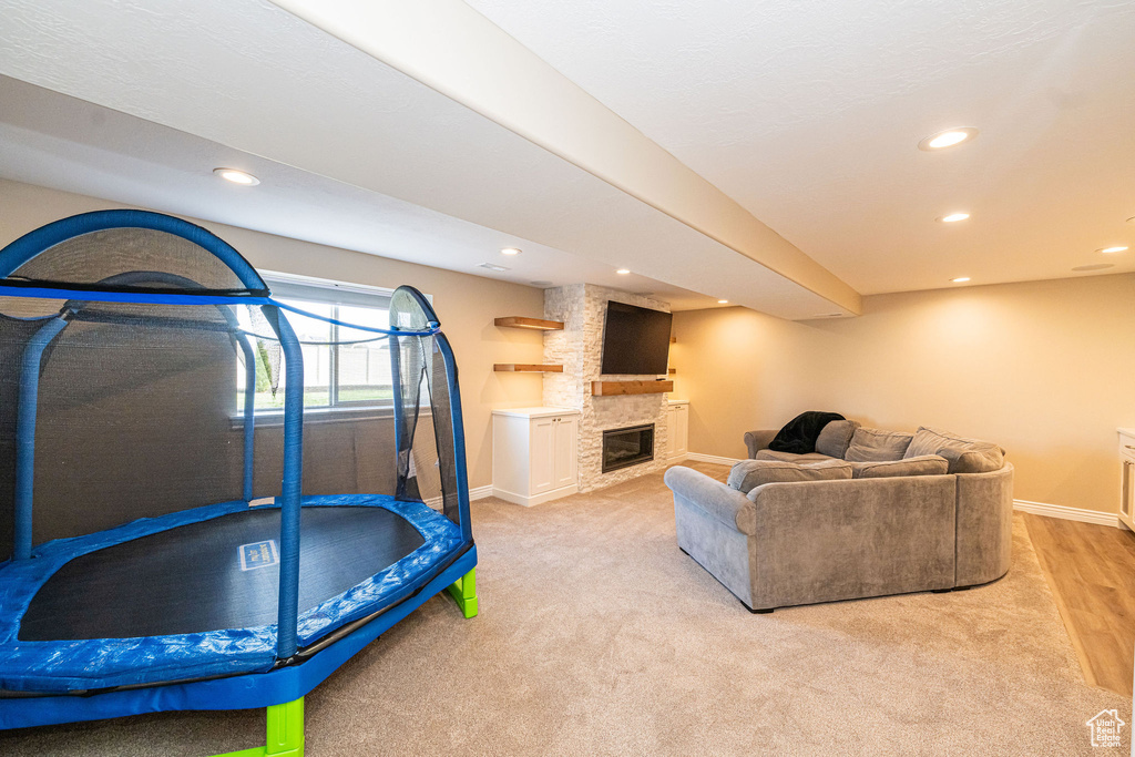 Recreation room featuring baseboards, recessed lighting, a stone fireplace, and carpet