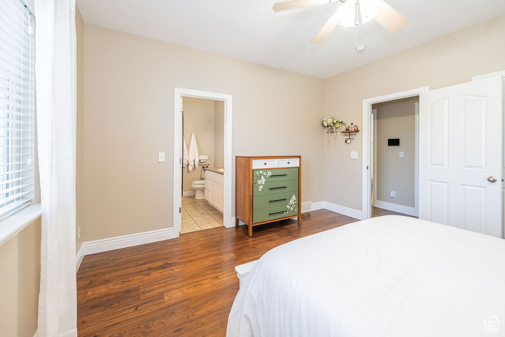 Bedroom with wood finished floors, baseboards, connected bathroom, and a ceiling fan