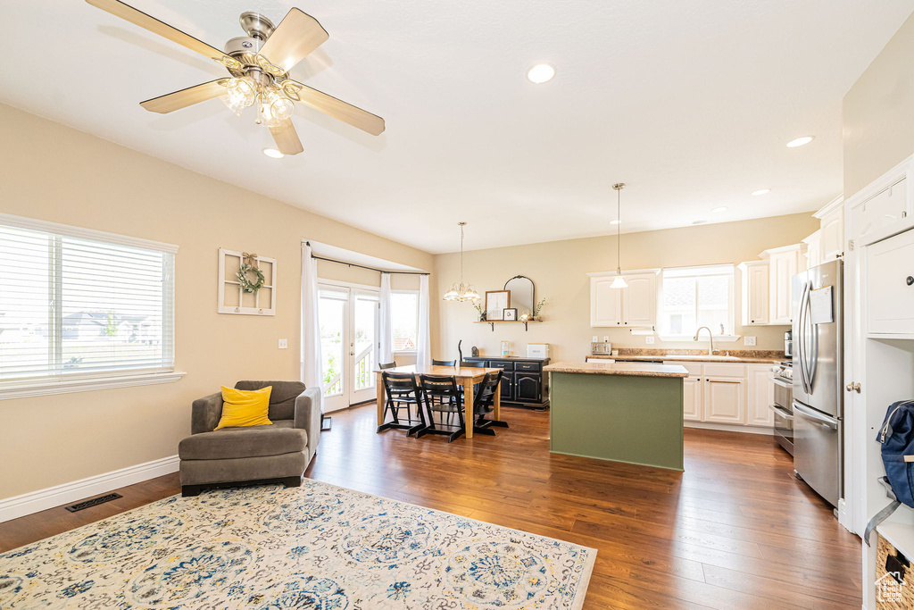 Kitchen with a center island, a sink, freestanding refrigerator, dark wood finished floors, and white cabinetry