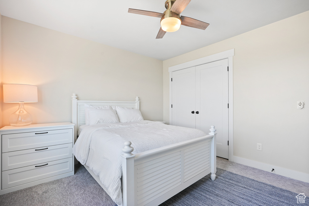 Bedroom featuring light carpet, a ceiling fan, and a closet
