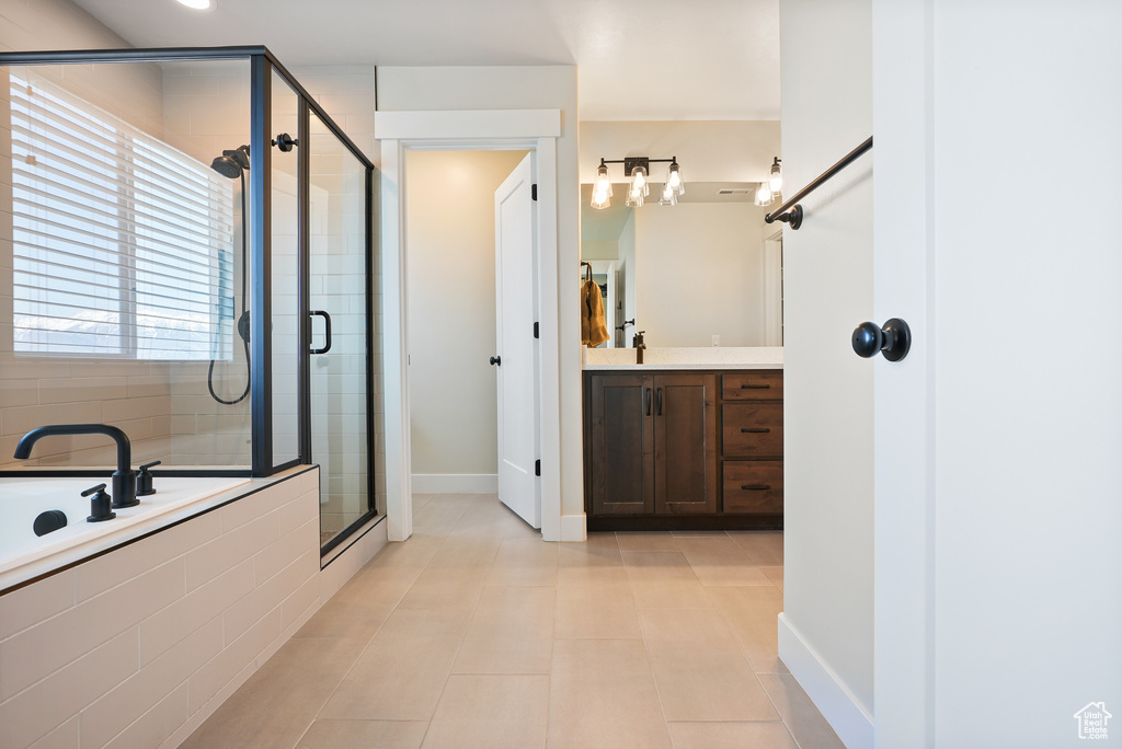 Bathroom with a shower stall, tile patterned flooring, vanity, a bath, and baseboards