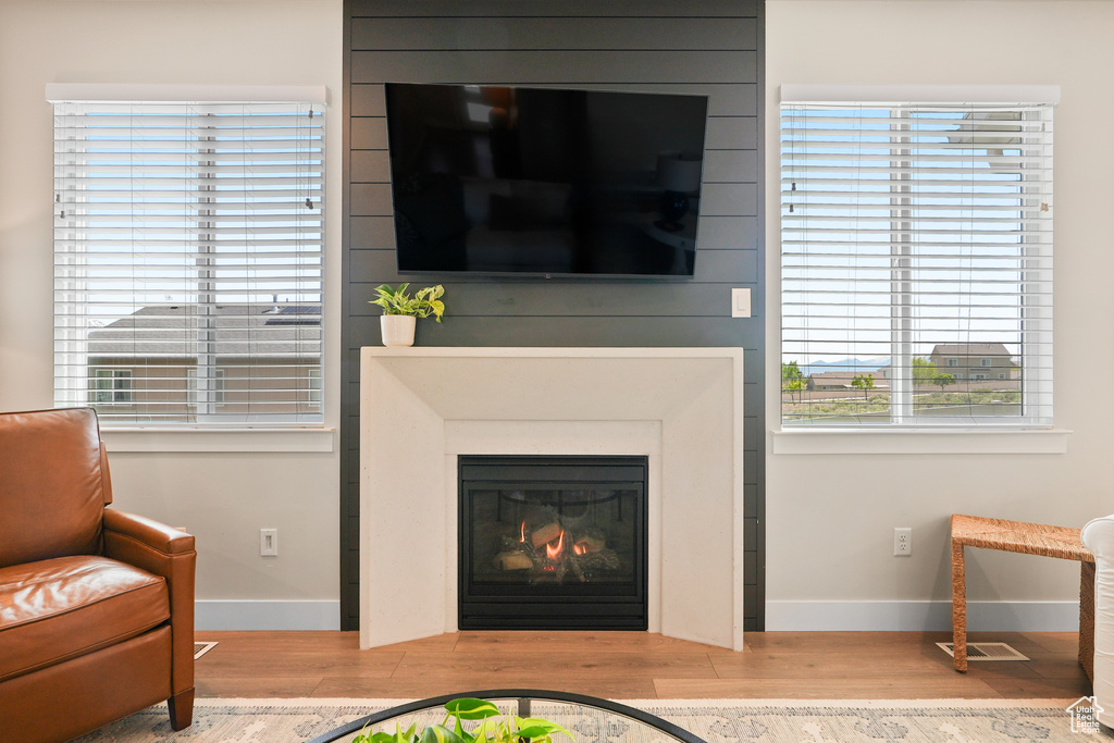 Living room featuring wood finished floors, healthy amount of natural light, a glass covered fireplace, and baseboards