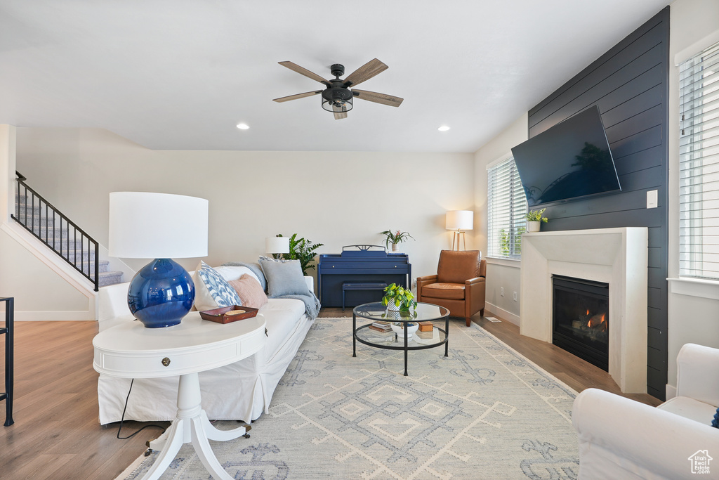 Living area with wood finished floors, ceiling fan, stairway, recessed lighting, and a large fireplace