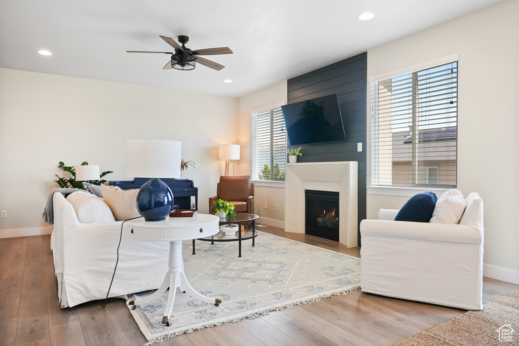 Living room featuring a ceiling fan, baseboards, wood finished floors, a large fireplace, and recessed lighting