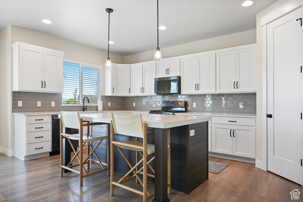 Kitchen featuring range with gas stovetop, stainless steel microwave, light countertops, wood finished floors, and recessed lighting