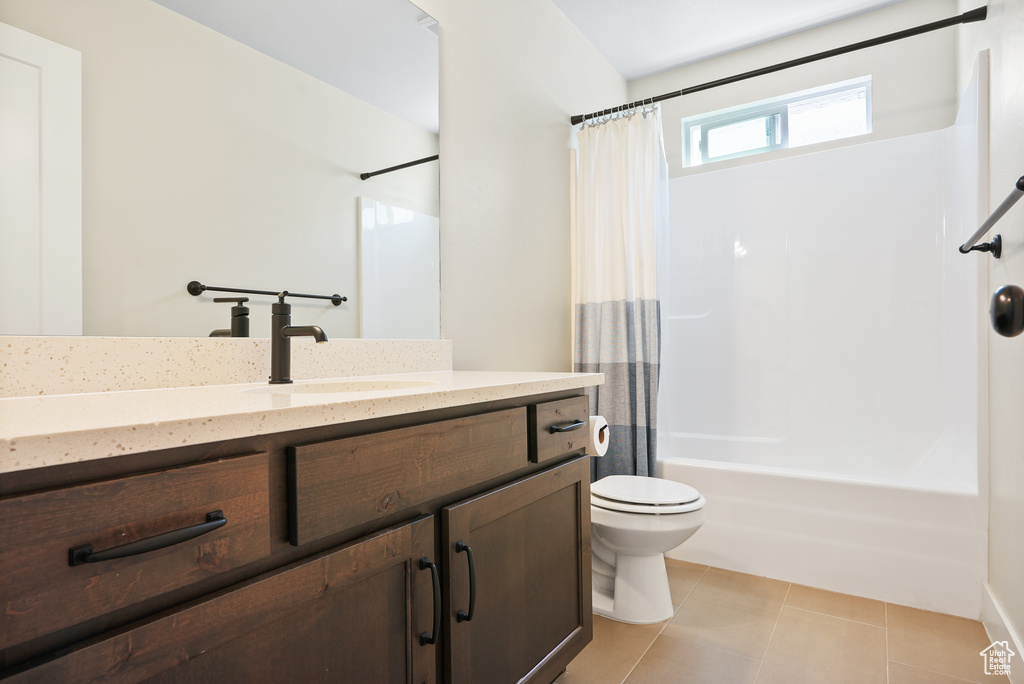 Full bath with toilet, tile patterned flooring, shower / bath combo with shower curtain, and vanity
