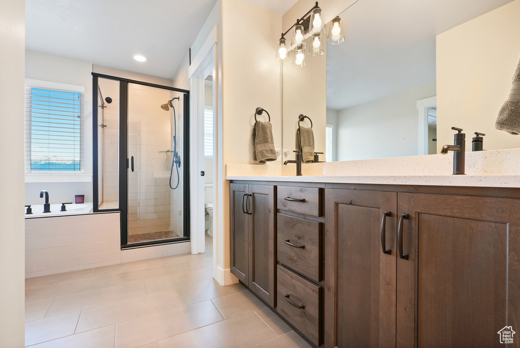 Bathroom featuring a shower stall, tile patterned flooring, double vanity, toilet, and a bath