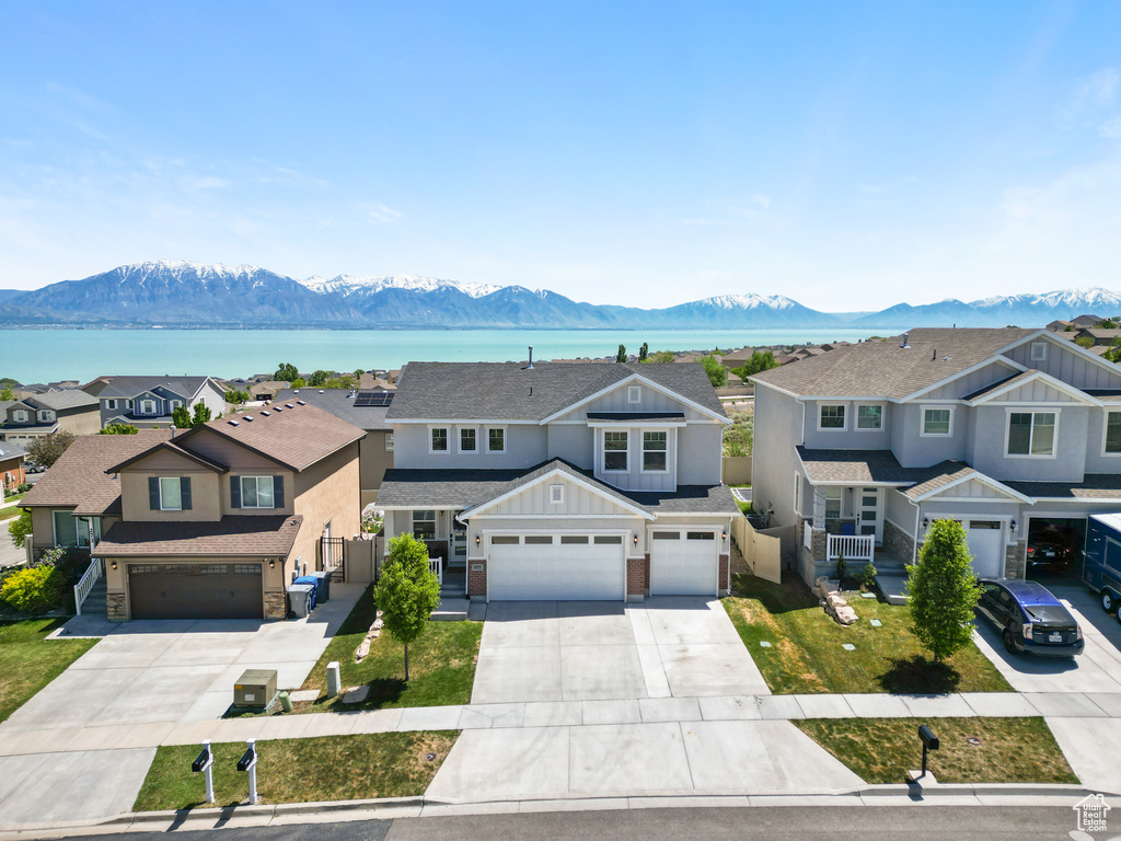 View of front of house featuring driveway, a water and mountain view, board and batten siding, and fence
