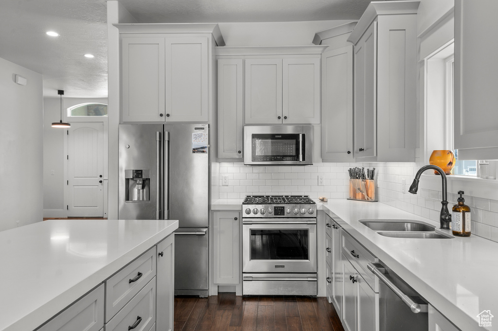 Kitchen with appliances with stainless steel finishes, a sink, light countertops, backsplash, and recessed lighting