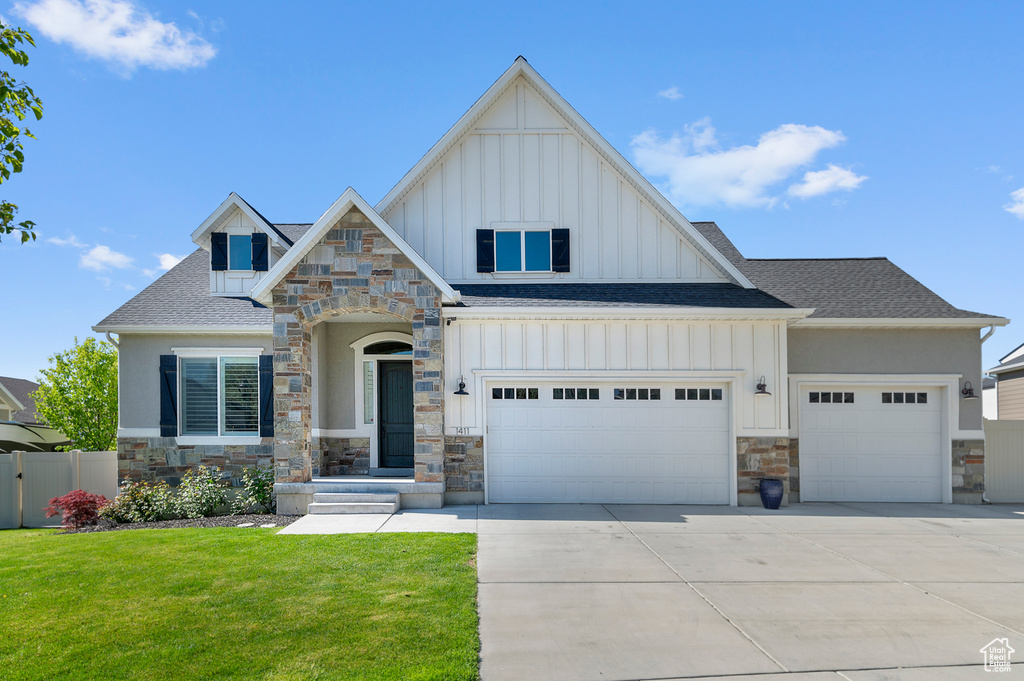 View of front facade featuring board and batten siding, stone siding, an attached garage, a shingled roof, and concrete driveway