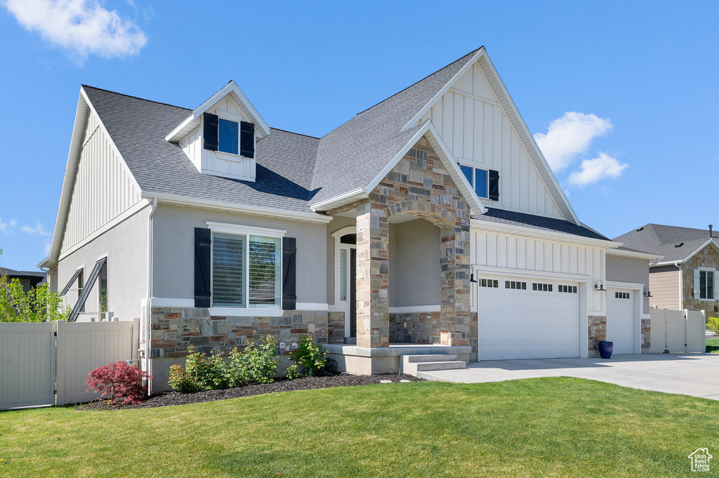 View of front of property featuring board and batten siding, stone siding, driveway, a shingled roof, and an attached garage