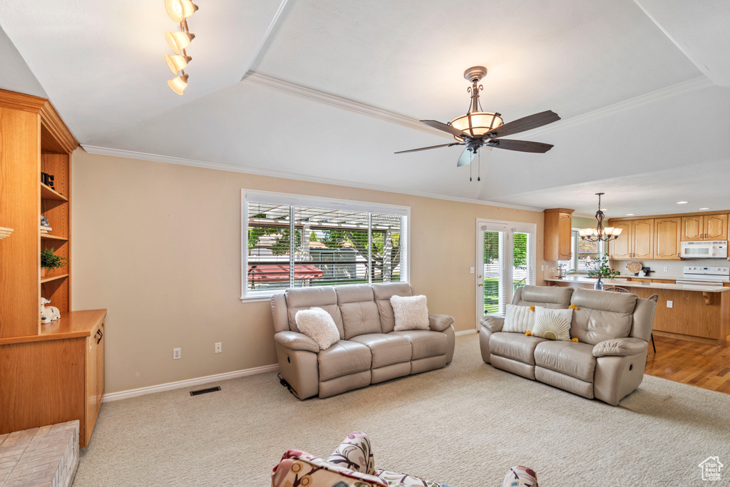 Living area with a ceiling fan, a chandelier, crown molding, baseboards, and light carpet