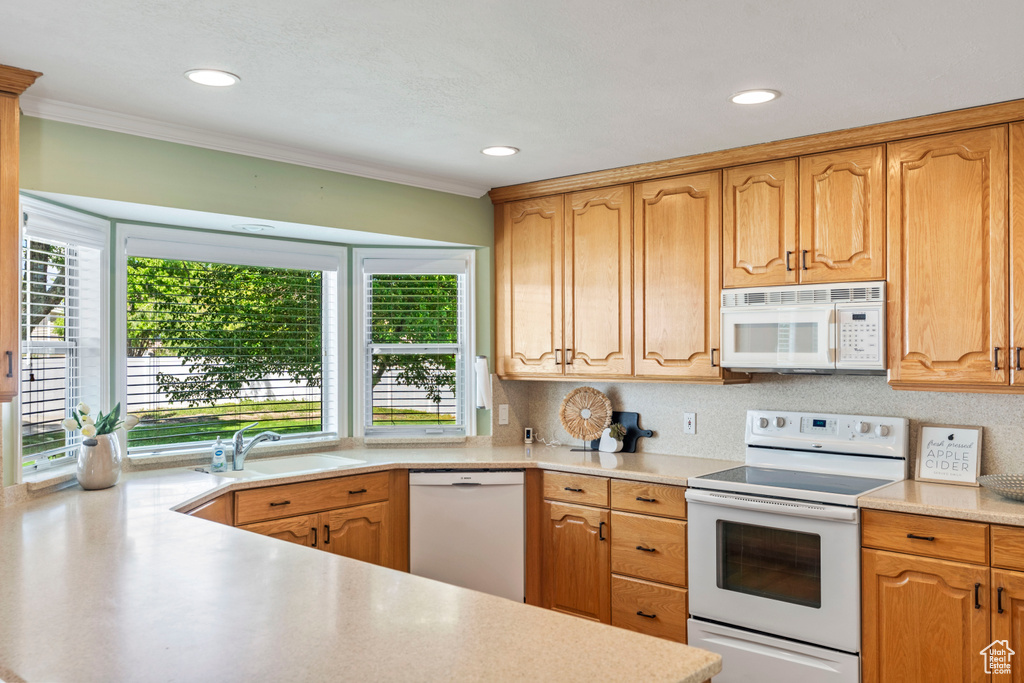 Kitchen featuring white appliances, a sink, plenty of natural light, light countertops, and recessed lighting
